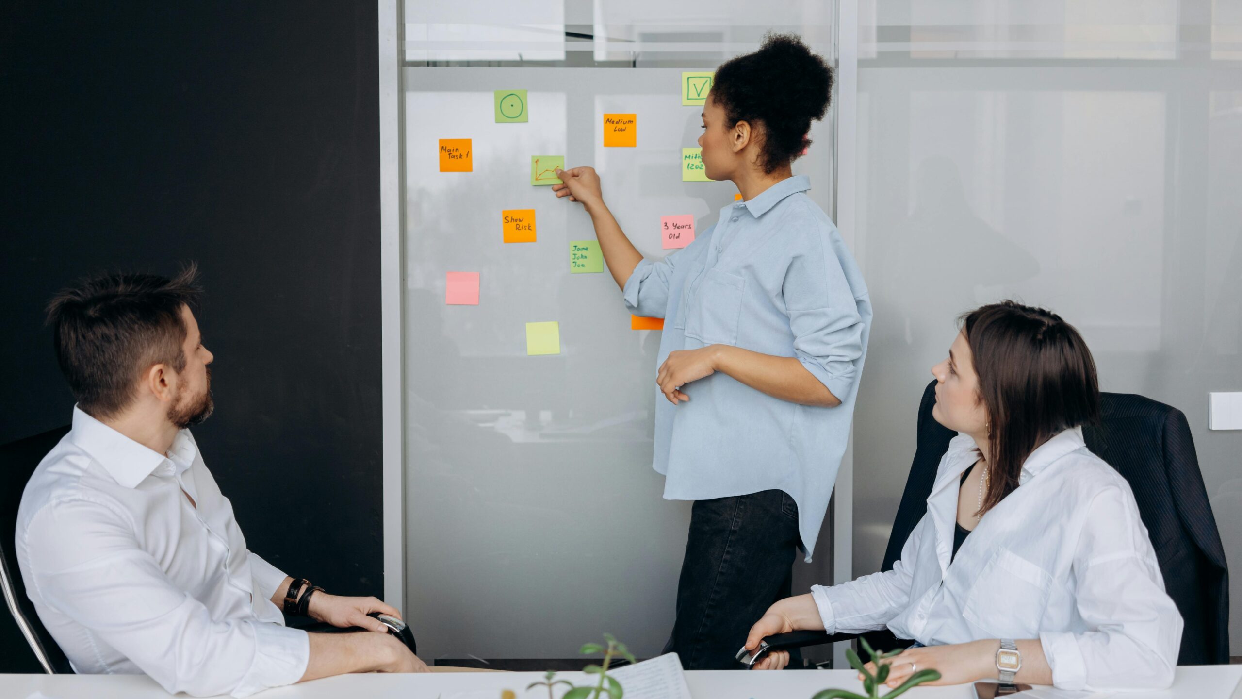 Business team collaborating and brainstorming in a meeting room with sticky notes.